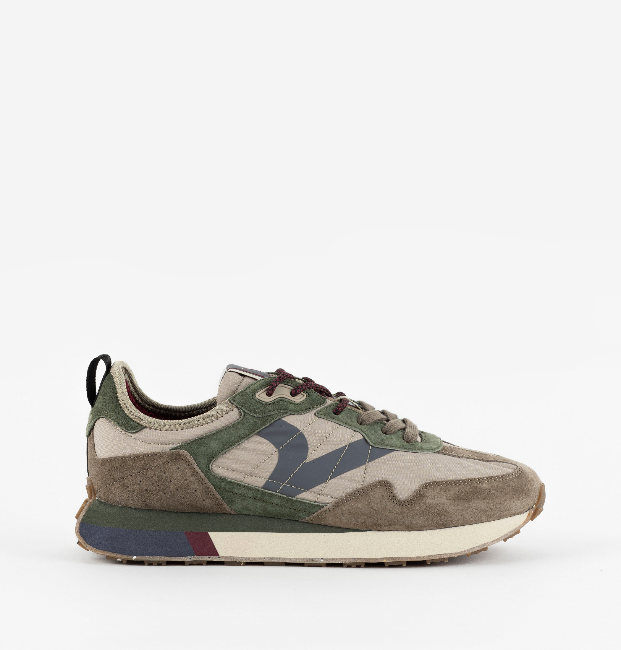 Zapatilla streetwear retro runner con ante verde y caqui, detalles marrones y suela de goma dentada.